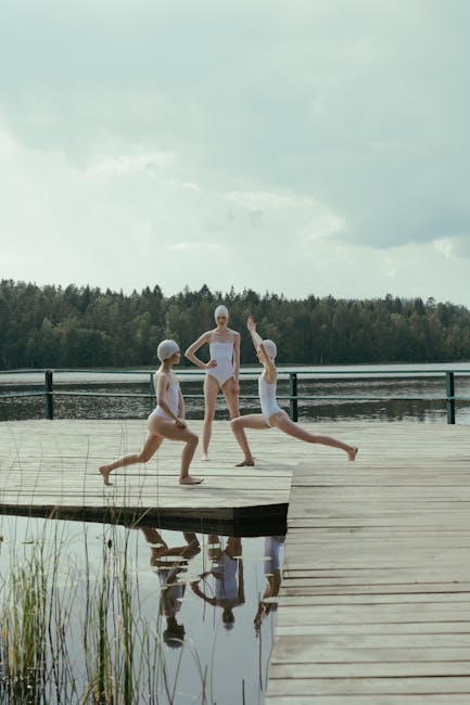 Woman practicing yoga on a wooden pier by a serene lake at sunrise